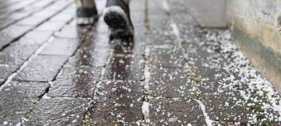 Closeup of technical salt grains on icy sidewalk surface in winter, used for melting ice and snow