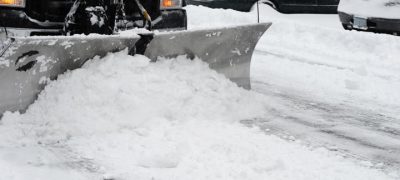 snow truck plowing the road, cars on the side of the road covered with snow